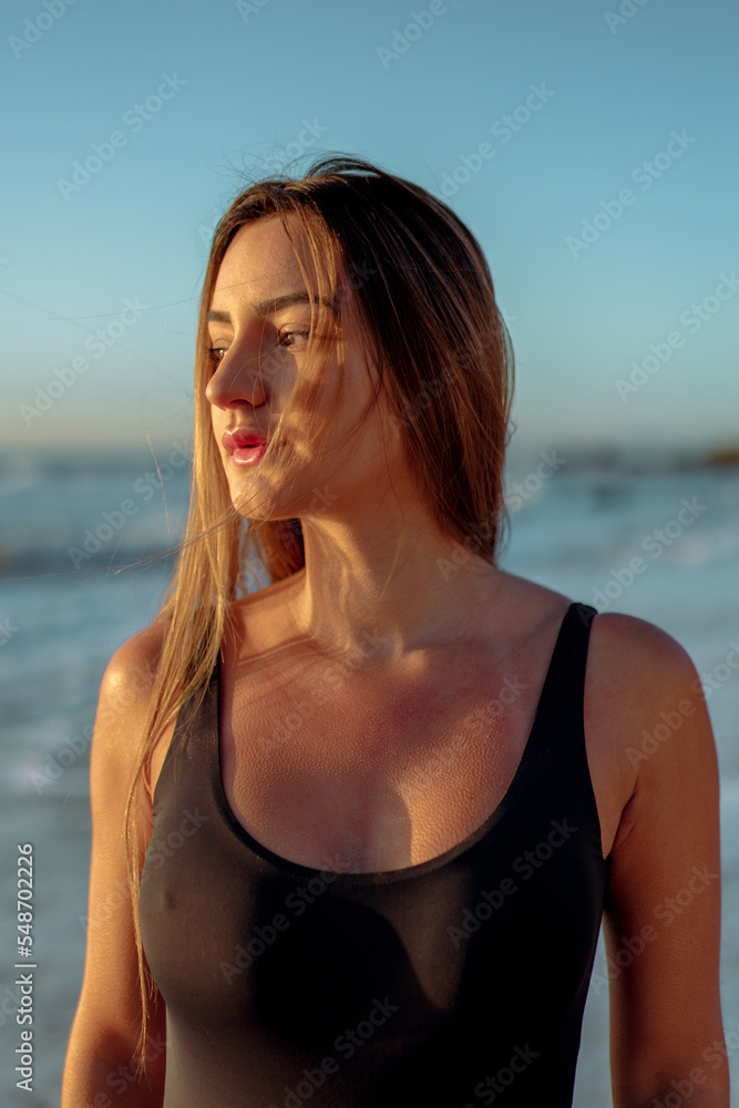 Jovem mulher de maiô preto no por do sol na praia