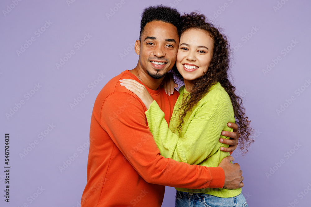 Side profile view smiling young couple two friends family man woman of African American ethnicity wear casual clothes together look camera cuddle hug isolated on pastel plain light purple background. Side profile view smiling young couple two friends family man woman of African American ethnicity wear casual clothes together look camera cuddle hug isolated on pastel plain light purple background.