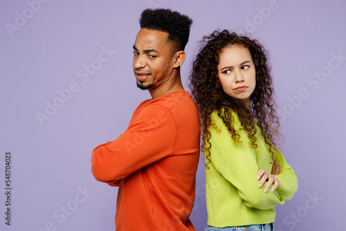 Side view sad young couple two friend family man woman of African American ethnicity in casual clothes together stand back to back hold hands crossed folded isolated on plain light purple background © ViDi Studio