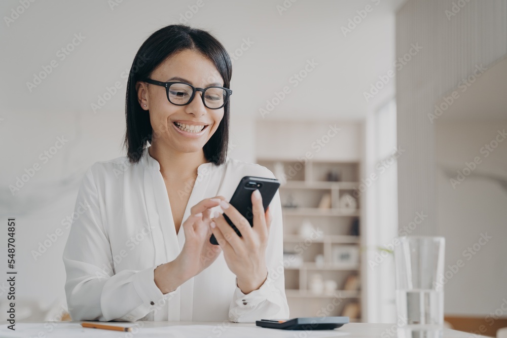 Φωτογραφία Happy businesswoman in glasses uses mobile apps for business, holding smartphone