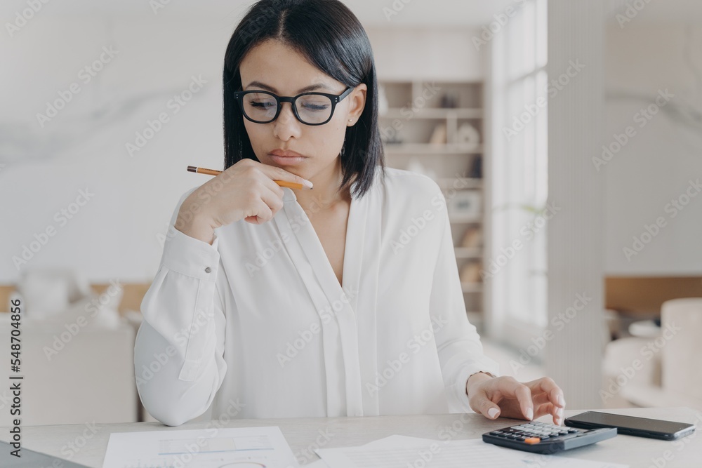 Φωτογραφία Businesswoman in glasses counts profit on calculator, analyzes company budget