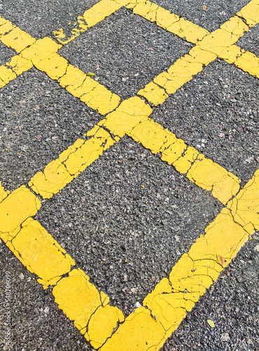 No parking area sign on the asphaltic surface, Yellow crossing sign on the textured floor, Yellow logo on grey color background