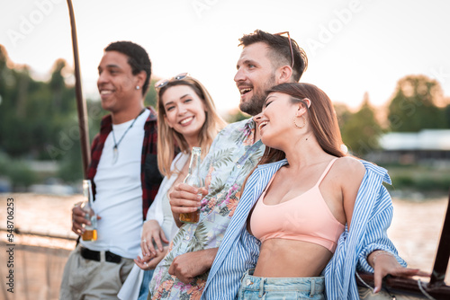 Group of multietnical friends enjoying on river boat party, drinking beer having a great time