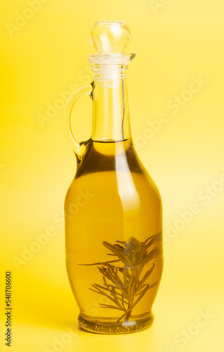 Jug with olive oil, on yellow background.