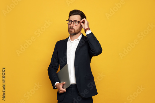 Portrait of bearded man with glasses and laptop on orange background © New Africa