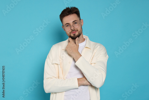 Handsome man in white jacket and eyeglasses with on light blue background