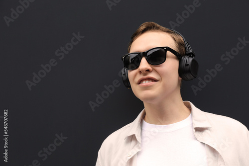 Handsome young man with headphones near black wall. Space for text © New Africa