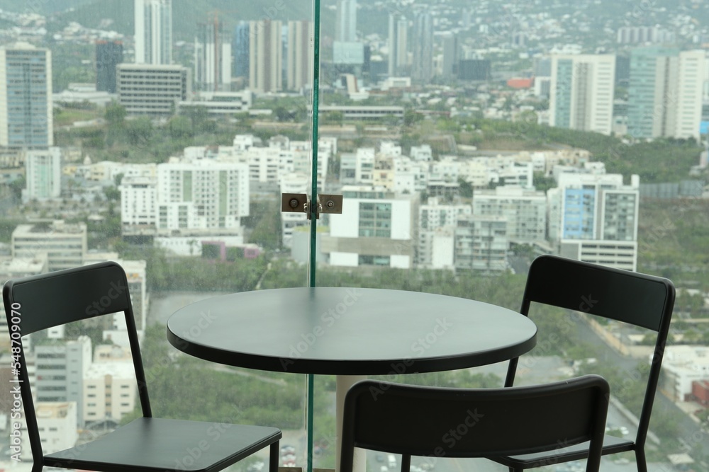 Obraz premium Coffee table and chairs against picturesque landscape of city in cafe