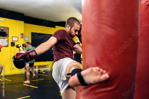 Kickboxing fighter performing Kicks with foot on punching bag at the gym © santypan