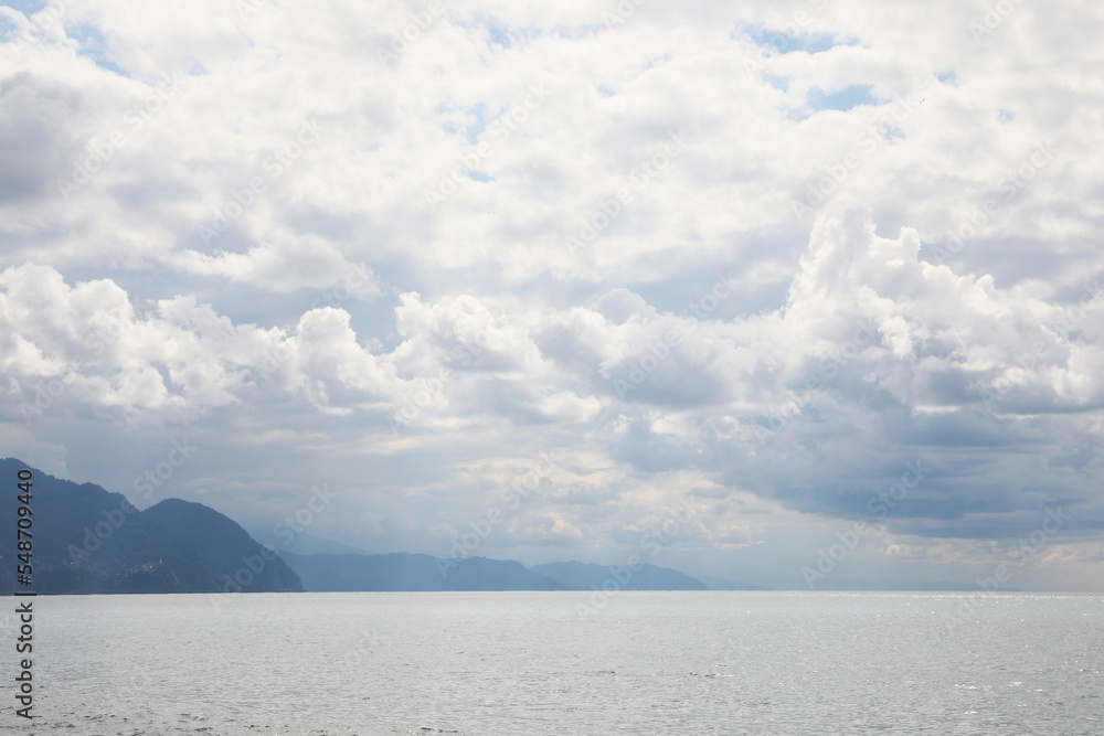Picturesque view of beautiful sea and mountains under sky with fluffy clouds