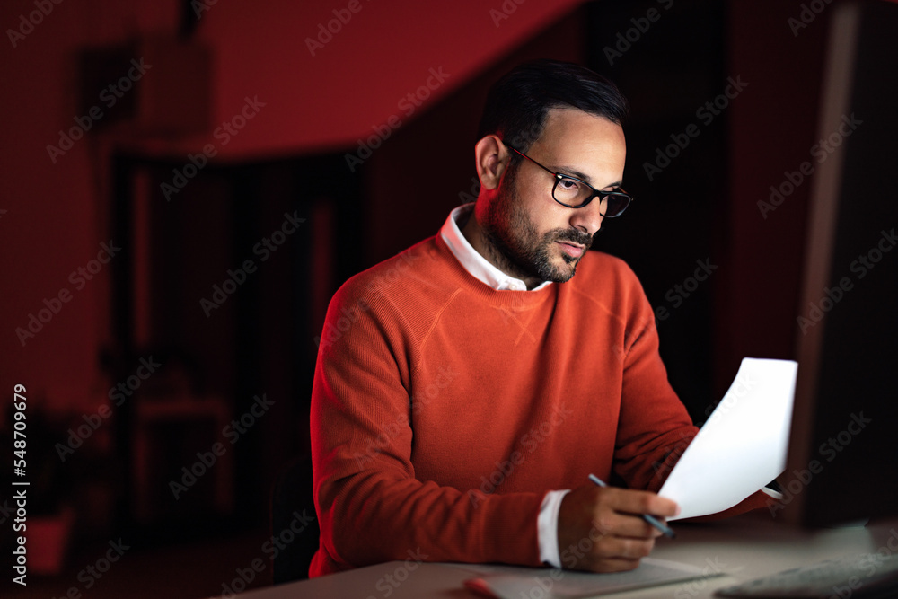 Focused male boss, reading one document, working overtime at the office. Focused male boss, reading one document, working overtime at the office.