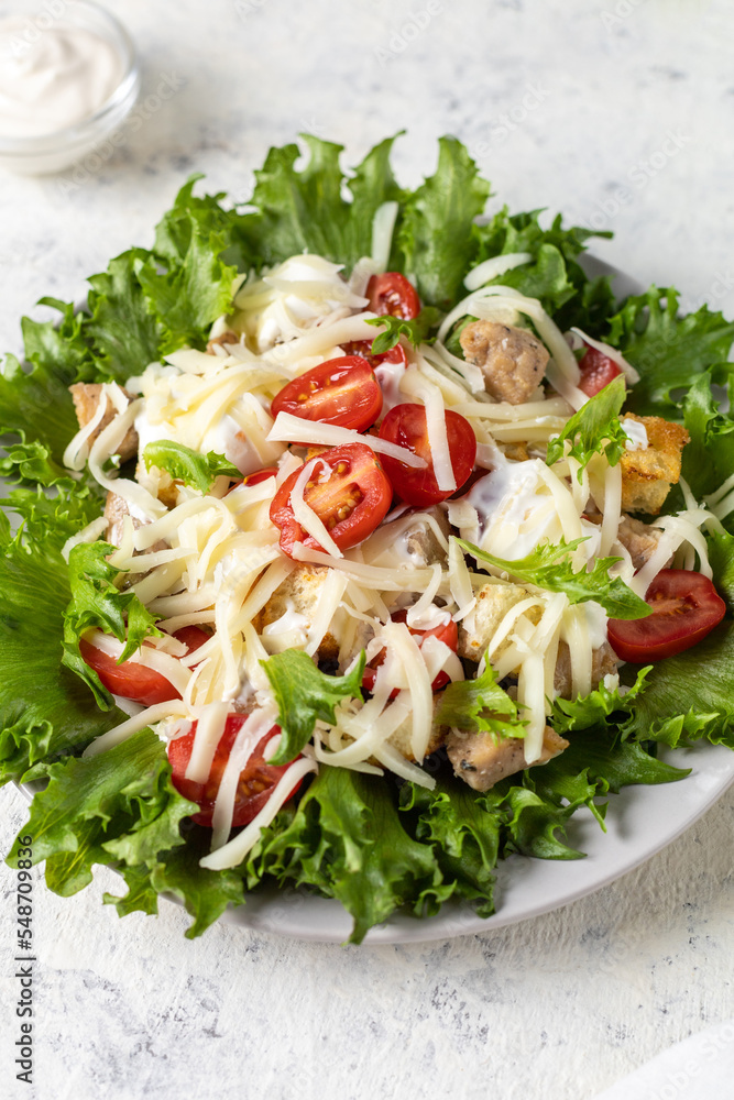 Traditional caesar salad with chicken on a plate on white table with napkin fork and knife. Traditional caesar salad with chicken on a plate on white table with napkin fork and knife.