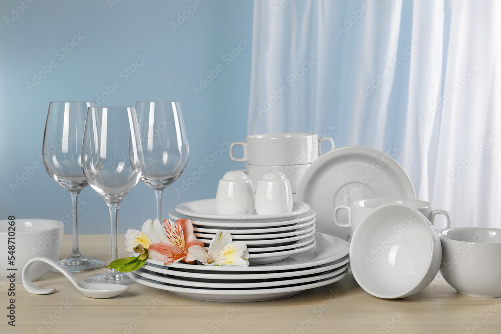 Fototapeta premium Glasses and clean dishware with flowers on light grey table