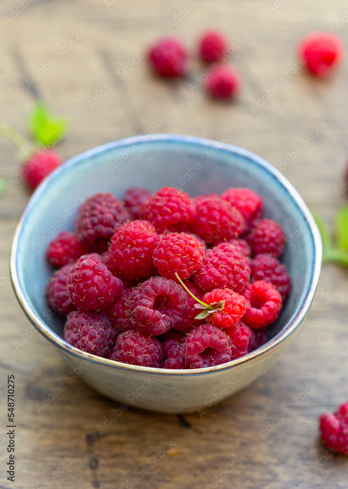 Bowl full of freshly gathered raspberries, close up, wooden background Bowl full of freshly gathered raspberries, close up, wooden background