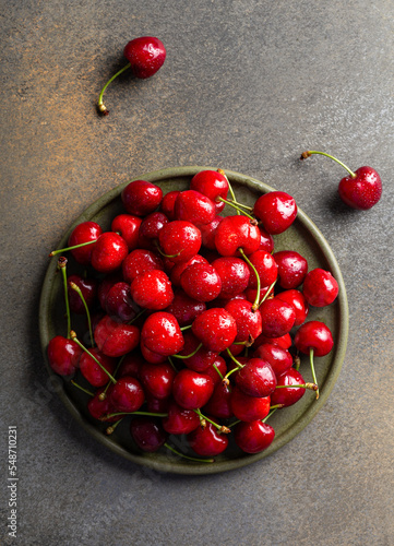 Ripe red sweet cherries on green ceramic plate, overhead shot