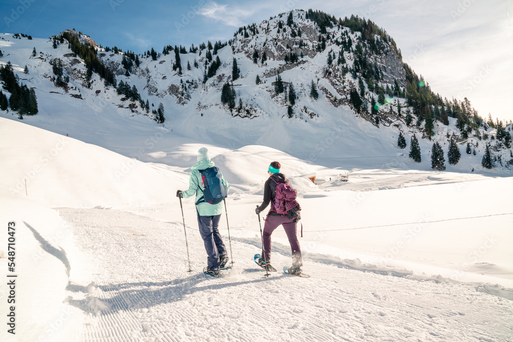 Schneeschuhlaufen im Winter. Ein Paar in den Bergen in einer verschneiten Winterlandschaft. Wintersport ausüben in der Schweiz.