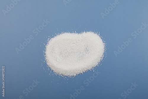 Pile of Sodium benzoate, sodium salt of benzoic acid on blue. White crystalline powder, chemical formula C6H5COONa. Food additive E211, Food Preservative also used in medicines and cosmetics photo