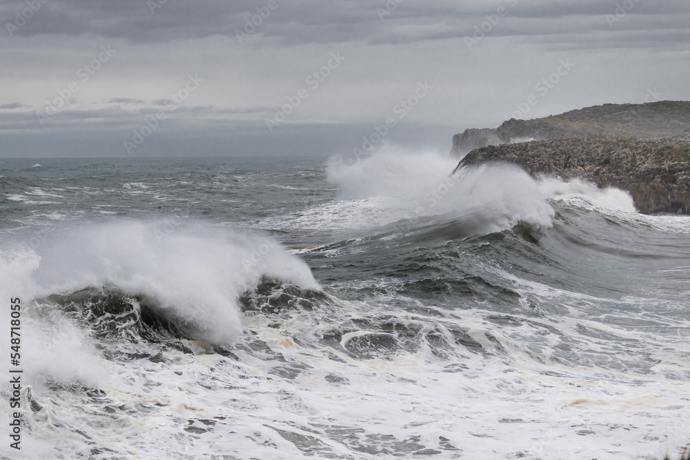 Huge waves crashing on the cliffs. Weather alert on the coast with strong wind and large waves. 
