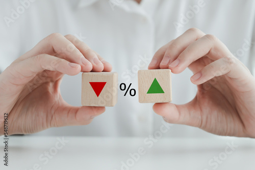 Percentage sign and hand holding wood block with direction of arrow that going down or up. Interest rate finance and mortgage rates concept. Business and financial, inflation, sale price, loan, tax.