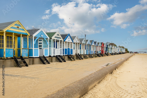 Obraz na plátně A row of colourful beach huts under a blue sky at Southwold beach in England