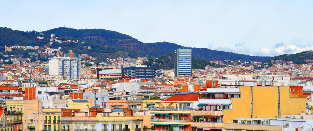 Roofs of buildings. Barcelona Spain, high angle view city skyline. Mountains skyline. Rooftop view in Barcelona. Facade of old residential building at hills and mountain. Historic building in rock.