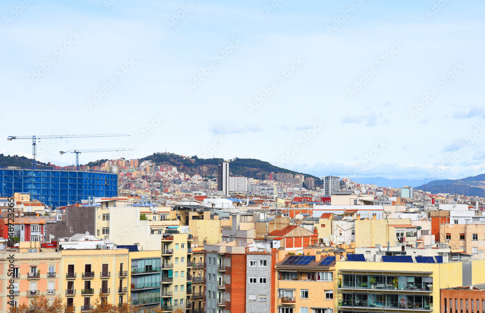 Roofs of buildings. Barcelona Spain, high angle view city skyline. Mountains skyline. Rooftop view in Barcelona. Facade of old residential building at hills and mountain. Historic building in rock.