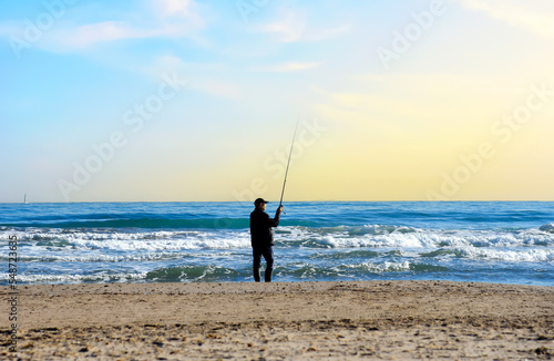 Fisherman catches fish on the coast near the sea. Catching fish in the sea from the shore. Fishing by the sea. Catching fish on spinning at ocean from the shore.