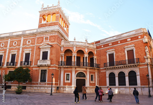 Archiepiscopal Palace of Valencia. Palace in the Old Town known as Cabildo de Valencia. Orange trees with Green leaves at facade building. Urban landscape. Ancient Architecture, Brick House.