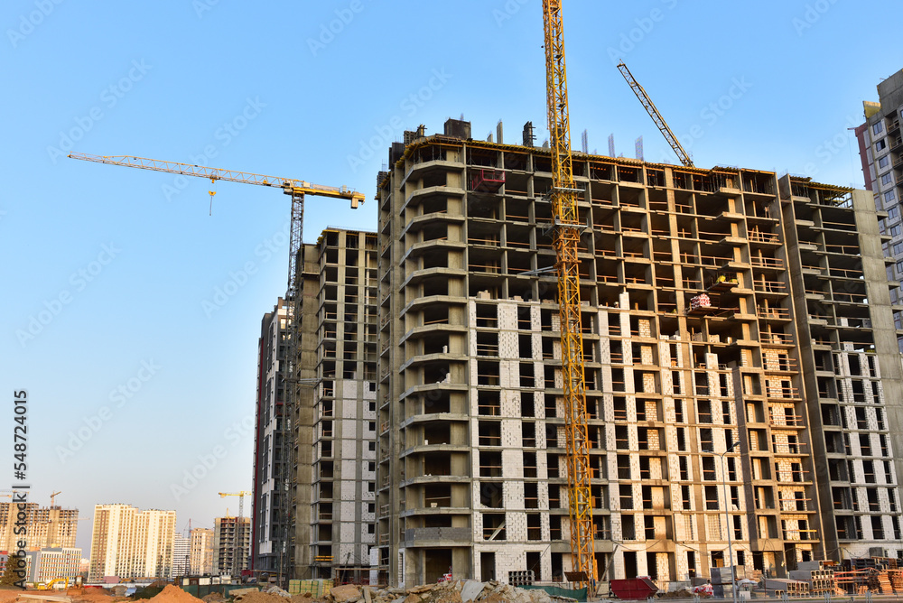 Сonstruction site with tower cranes on building construction. Builder on formworks. Cranes on pouring concrete in formwork. Tower cranes on construction in built environment. Buildings renovation.. Сonstruction site with tower cranes on building construction. Builder on formworks. Cranes on pouring concrete in formwork. Tower cranes on construction in built environment. Buildings renovation..