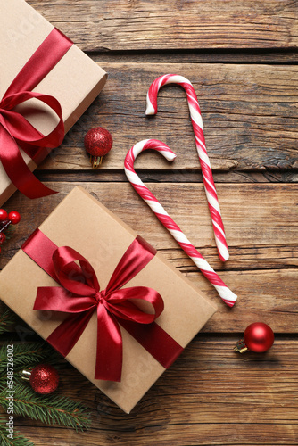 Gift box, candy canes and Christmas decor on wooden table, flat lay