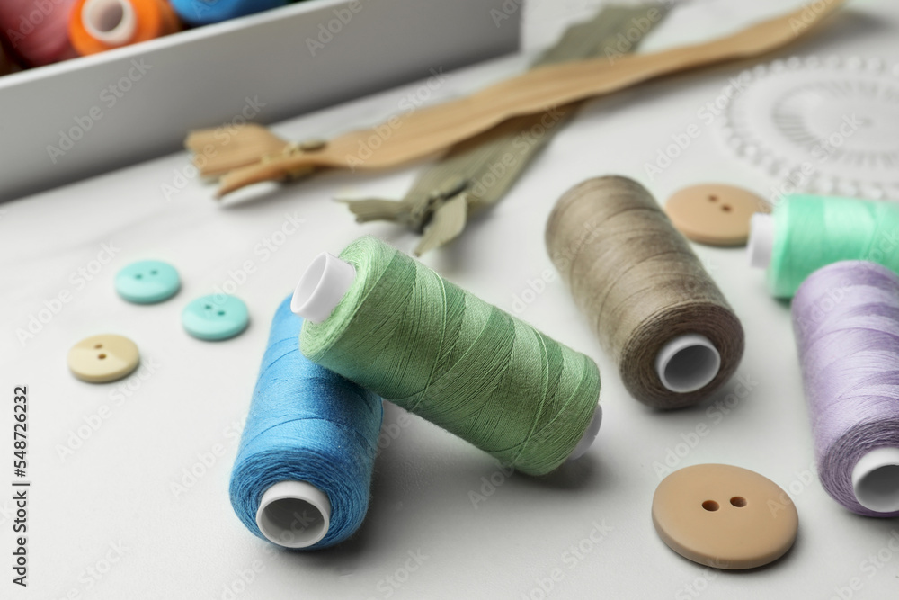 Sewing threads and buttons on white marble table, closeup Sewing threads and buttons on white marble table, closeup