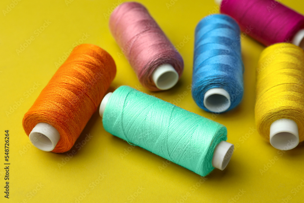 Different colorful sewing threads on yellow background Different colorful sewing threads on yellow background