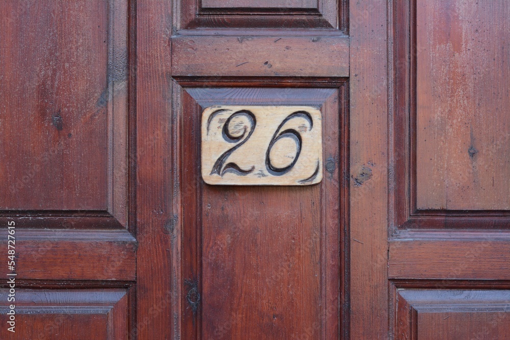 Plate with house number twenty six on wooden door, closeup Plate with house number twenty six on wooden door, closeup