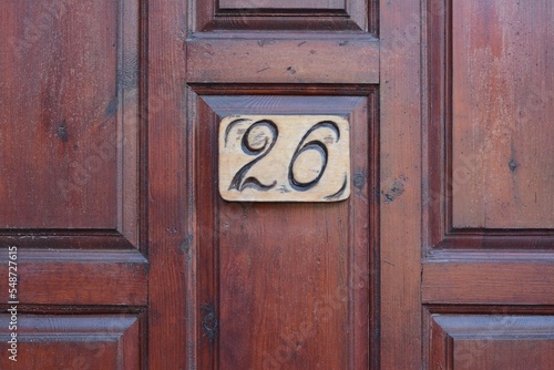 Plate with house number twenty six on wooden door, closeup