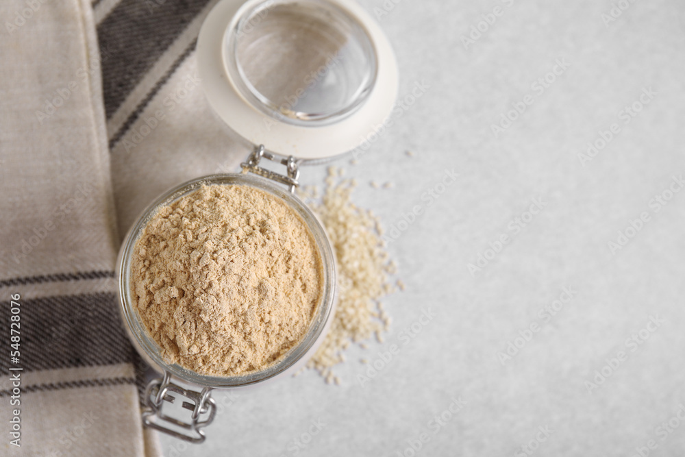 Sesame flour in glass jar on grey table, top view. Space for text. Sesame flour in glass jar on grey table, top view. Space for text.