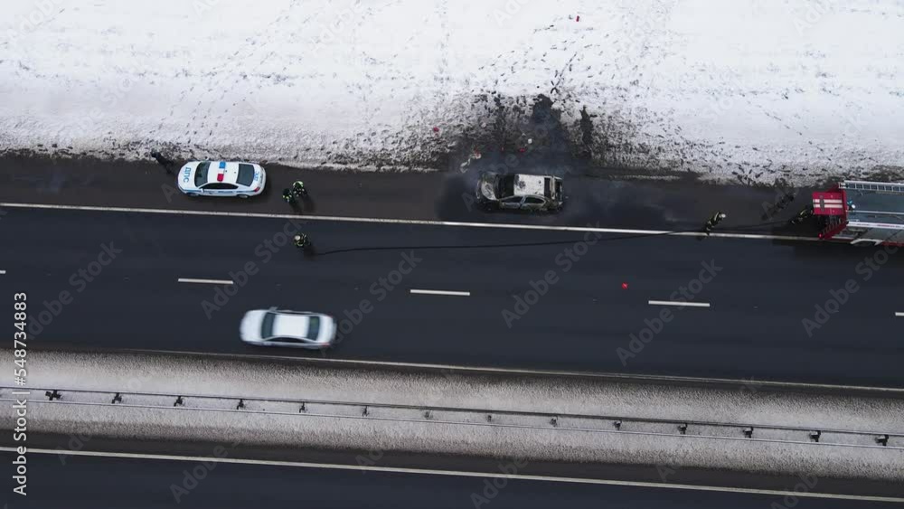Losses - a burned-out car on the edge of the motorway, aerial view. Near the fire and police cars. Help and rescue concept, 911 service. White snow on the side of the road. UHD 4K Losses - a burned-out car on the edge of the motorway, aerial view. Near the fire and police cars. Help and rescue concept, 911 service. White snow on the side of the road. UHD 4K