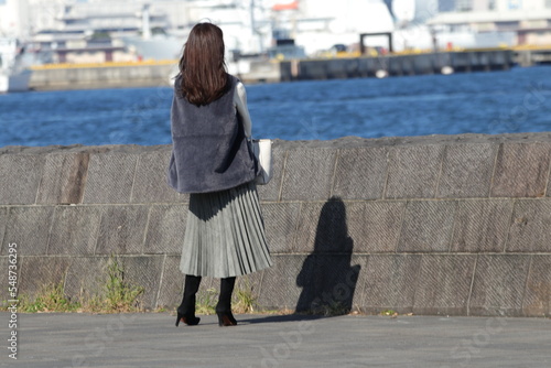 防波堤で一人で遠くを眺める若い女性