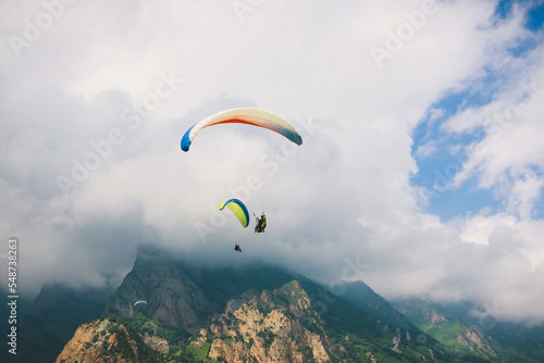 Paragliders are flying over mountains in cloudy summer day over the Chegem gorge, Caucasus
