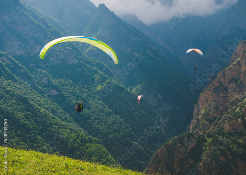 Paragliders are flying over mountains in summer day over the Chegem gorge, Caucasus