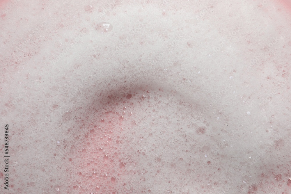 Fluffy soap foam on pink background, closeup
