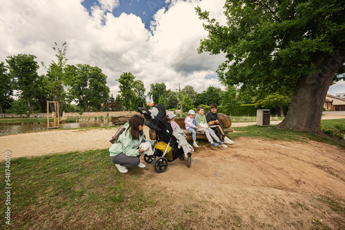 Mother with kids sitting and having rest in wooden bench outdoor in park. photo