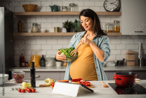Beautiful pregnant woman preparing delicious food. Smiling woman preparing delicious food.