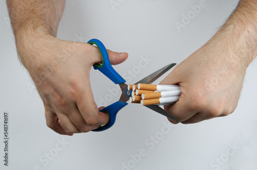 Quit smoking: hands with scissors cutting a cigarettes