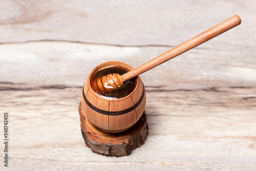 Close up dark honey in a wooden barrel and dipper
