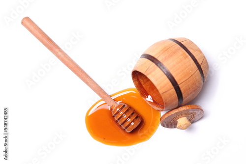 Dark honey spilled from the barrel on a white background