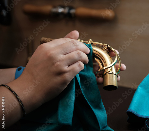 woman's hands cleaning a saxophone neck in an instrument repair shop