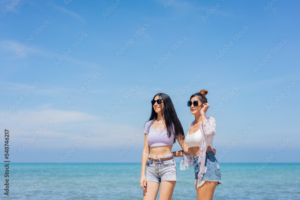 Two girlfriends hugging up and enjoying on the sea beach. A pair of girls in love cuddling on a tropical beach. romantic young lesbian couples in love and walking together on the beach.Concept of LGBT Two girlfriends hugging up and enjoying on the sea beach. A pair of girls in love cuddling on a tropical beach. romantic young lesbian couples in love and walking together on the beach.Concept of LGBT