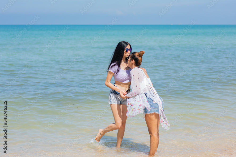 Two girlfriends hugging up and enjoying on the sea beach. A pair of girls in love cuddling on a tropical beach. romantic young lesbian couples in love and walking together on the beach.Concept of LGBT Two girlfriends hugging up and enjoying on the sea beach. A pair of girls in love cuddling on a tropical beach. romantic young lesbian couples in love and walking together on the beach.Concept of LGBT