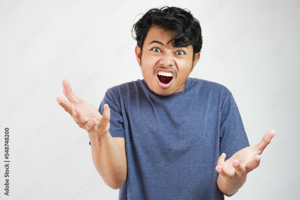 Fototapeta premium Handsome young Asian man wearing casual t-shirt standing over white background and madly screaming and shouting with aggressive expression and raised hands. Frustration concept.