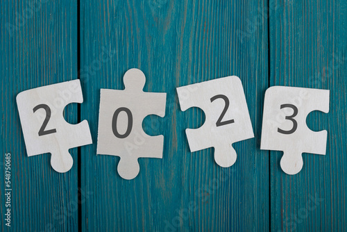 business concept - puzzle pieces with text "2023" on a blue wooden background